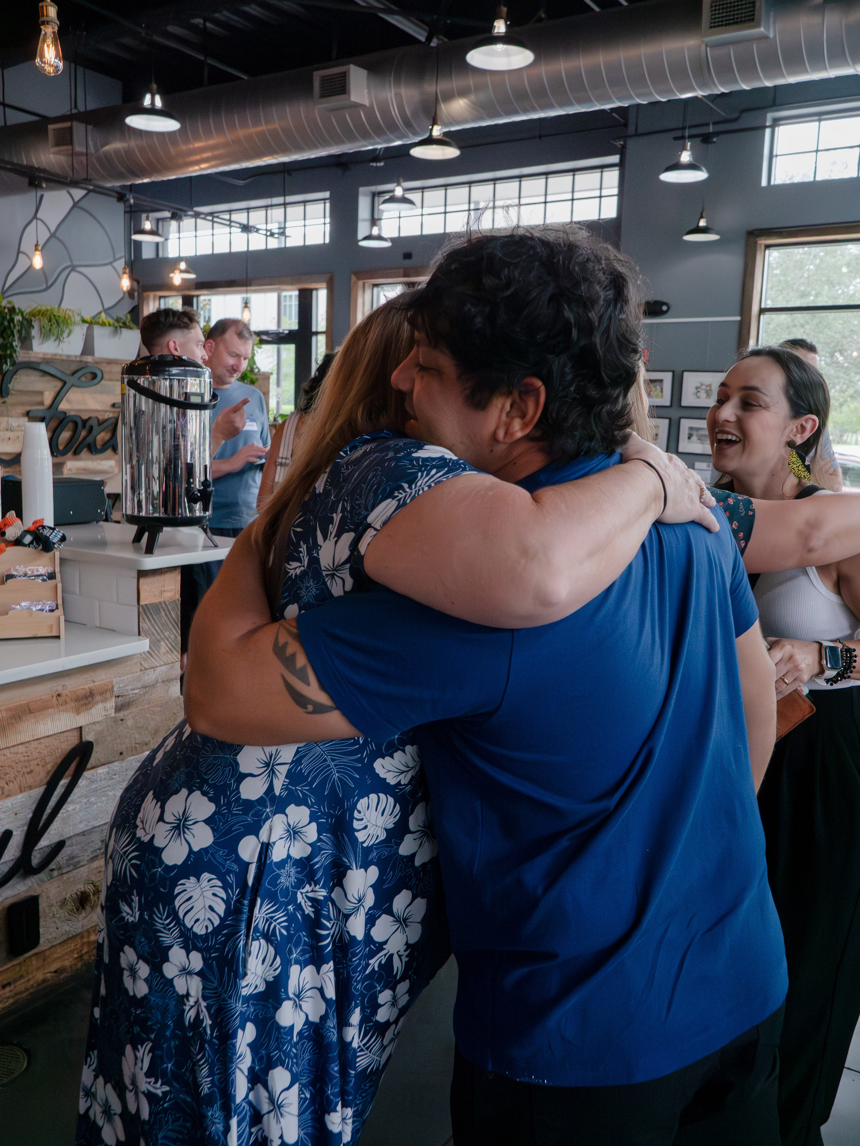 Two members of Church in the Garden share a warm embrace as another friend joins in