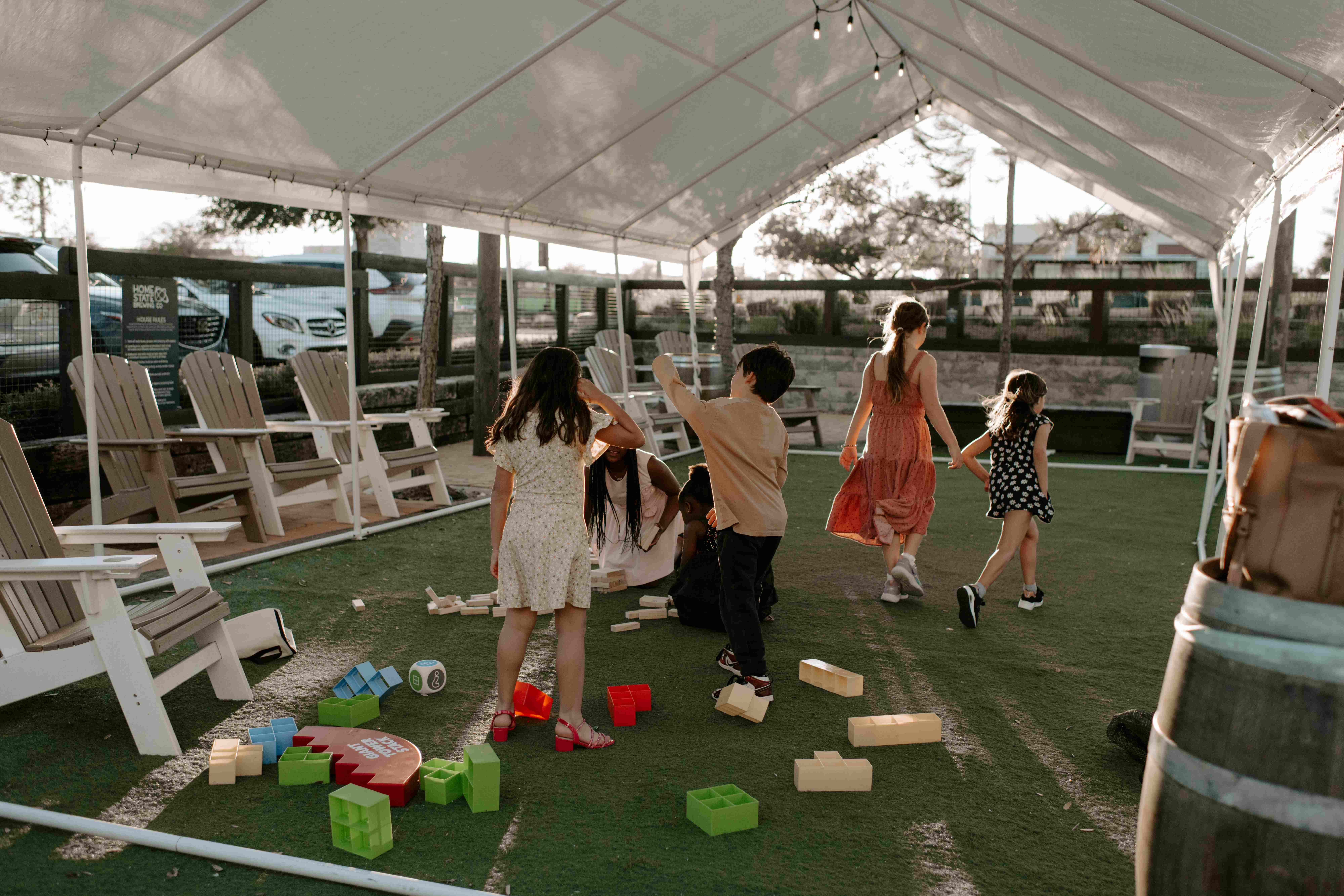 Children playing with giant stacking blocks and games outdoors at golden hour